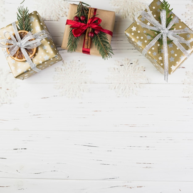 Set of present boxes in Christmas wrap between ornament snowflakes