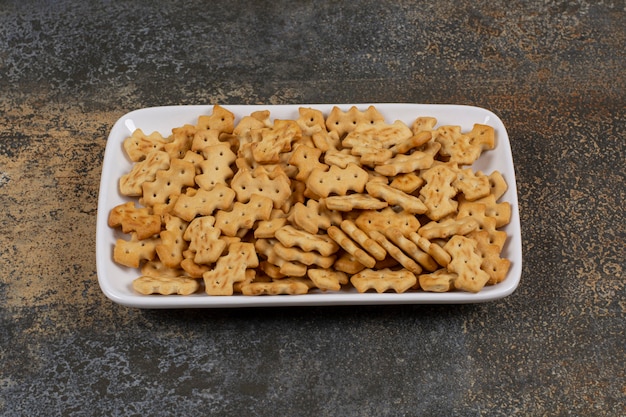 Set of salty crackers on white square plate.