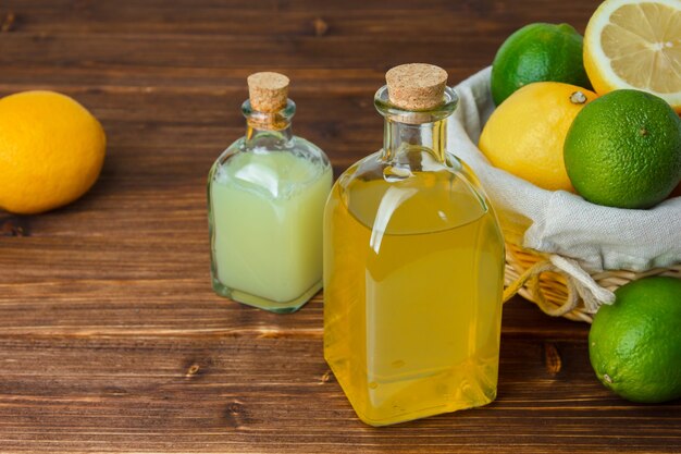 Foto gratuita set di fette di limone e cesto con follato con limoni e succo di limone in un cesto su una superficie di legno. vista dall'alto.