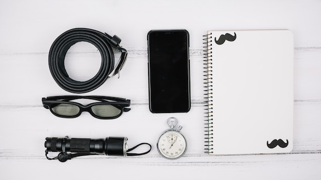 Set of smartphone near notebook and male accessories