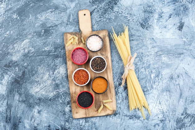 Foto gratuita set di spezie e spaghetti su intonaco grigio e sfondo tagliere. vista dall'alto.