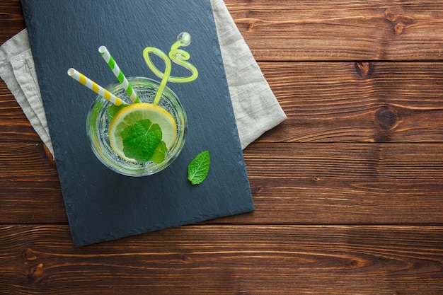 Set of straw, white cloth and sliced lemon in a bowl on a wooden background. top view. copy space for text