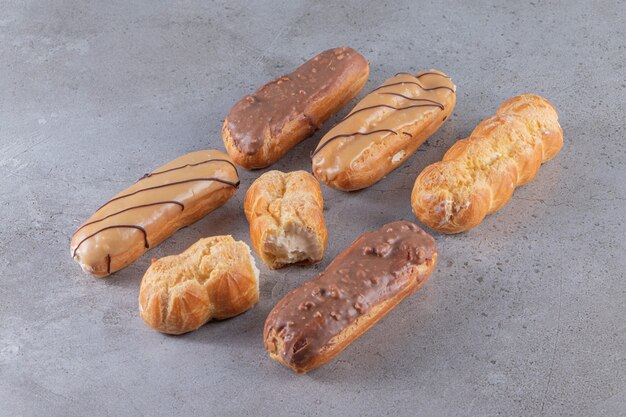 Set of sweet eclairs with various fillings on stone surface