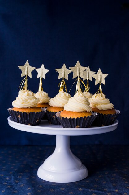 Set of tasty cakes with butter cream and stars on stand 