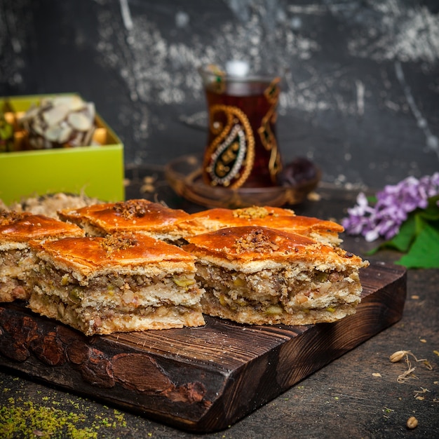 Set of tea, cookies and baklava on a wood and black background. side view.