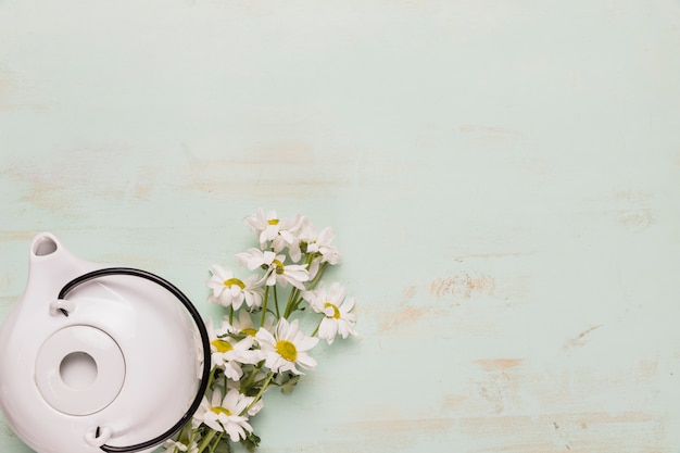 Free photo set of teapot and camomile bouquet