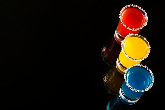 Set of three colored shot glasses with cocktails and copy space