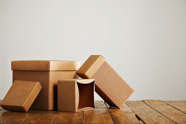 Set of three unlabeled similar craft cardboard boxes with covers beautifully arranged in a studio with white walls