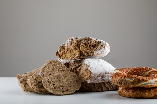 Набор турецких бублик и нарезанный хлеб на белой и серой поверхности. вид сбоку.