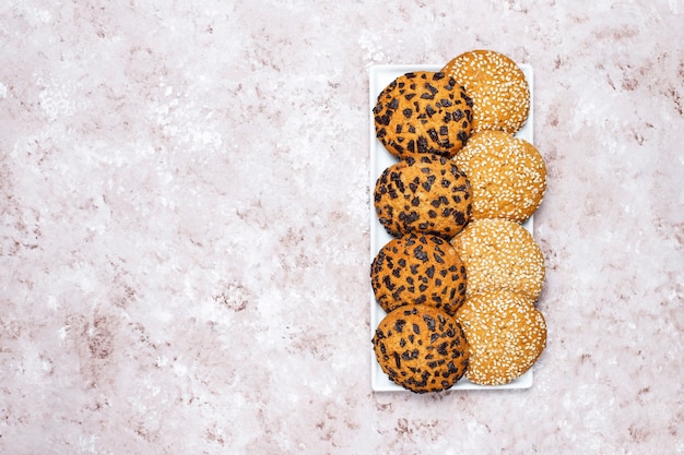 Set of various american style cookies on a light concrete background. Shortbread with confetti, sesame seed, peanut butter, oatmeal and chocolate chip cookies.