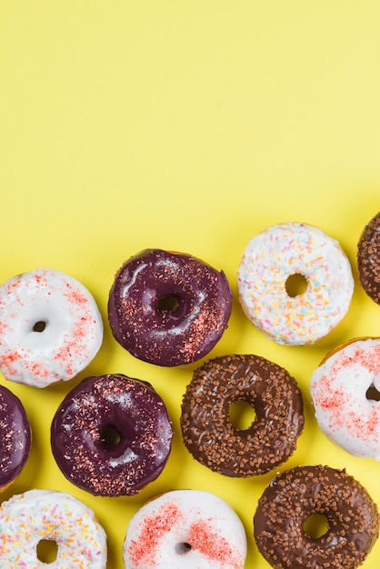 Set of various colorful donuts on yellow background