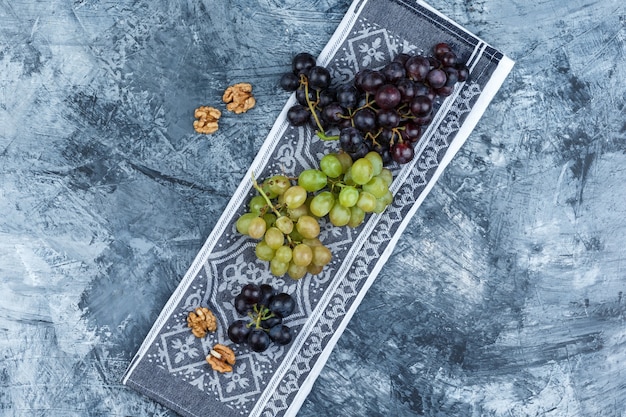 Free photo set of walnuts and grape bunches on grunge and kitchen towel background. flat lay.