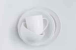 Foto gratuita set di utensili bianchi in una pila di tre piatti diversi e una tazza