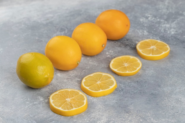 Set of whole sour lemons with slices on a marble background.