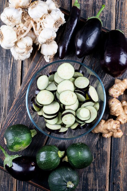 Set of zucchini, garlic, ginger and sliced eggplants in a bowl on a wooden table. top view.