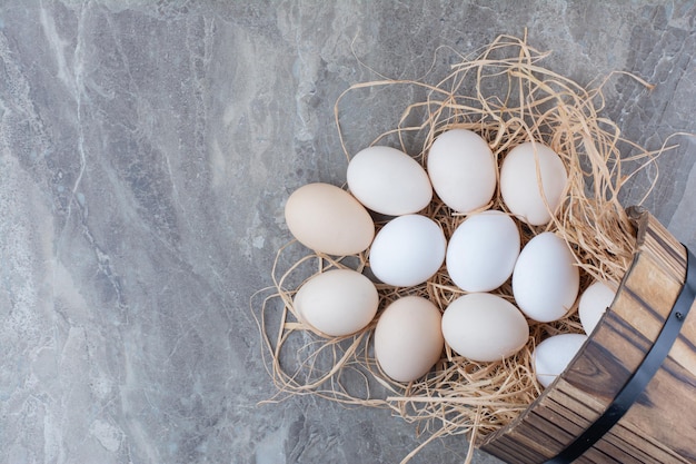 Several chicken fresh eggs on hay on marble background. High quality photo