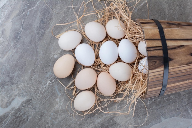 Several chicken fresh eggs on hay on marble background. High quality photo