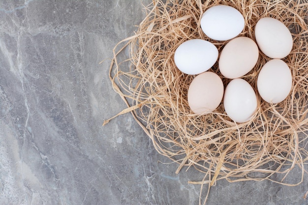 Several chicken fresh eggs on hay on marble background. High quality photo