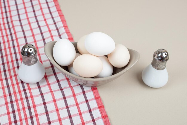 テーブルクロスの灰色のプレートにいくつかの新鮮な鶏の白い卵。