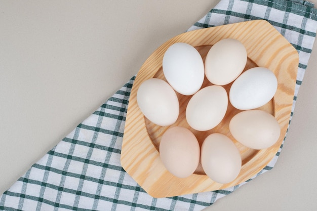 Несколько свежих куриных белых яиц на деревянной тарелке.