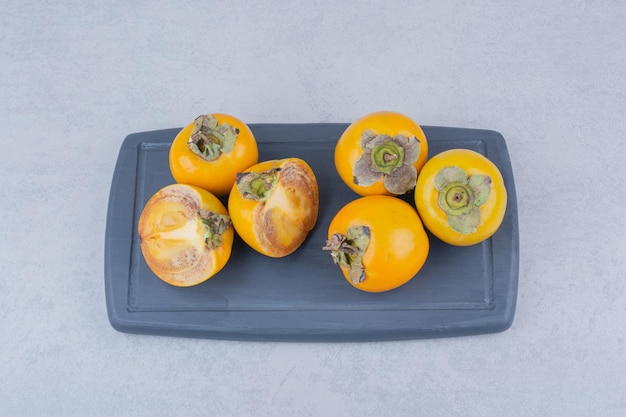 Several tasty persimmons on dark board . High quality photo