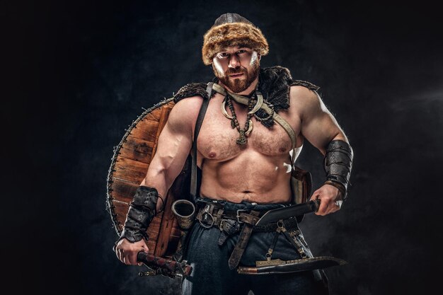 Severe barbarian in warrior clothes, posing on a dark background.