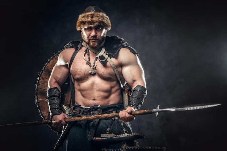 Free Photo severe barbarian in warrior clothes, posing on a dark background.
