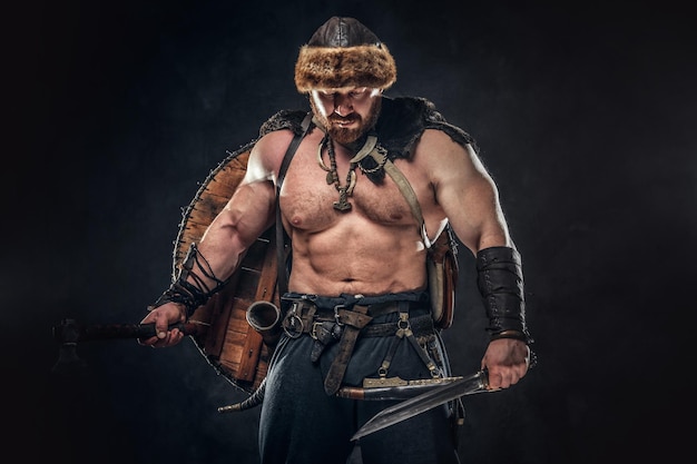 Free photo severe barbarian in warrior clothes, posing on a dark background.