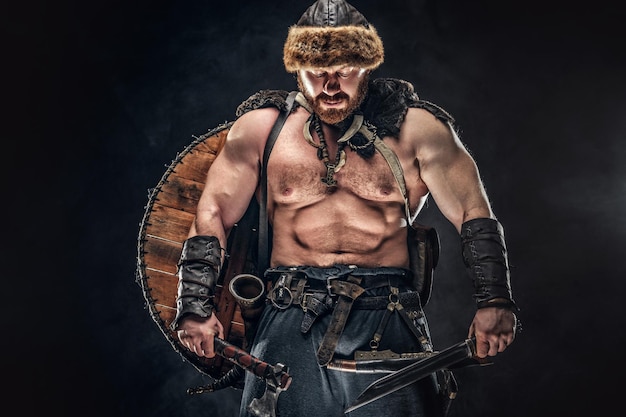 Severe barbarian in warrior clothes, posing on a dark background.