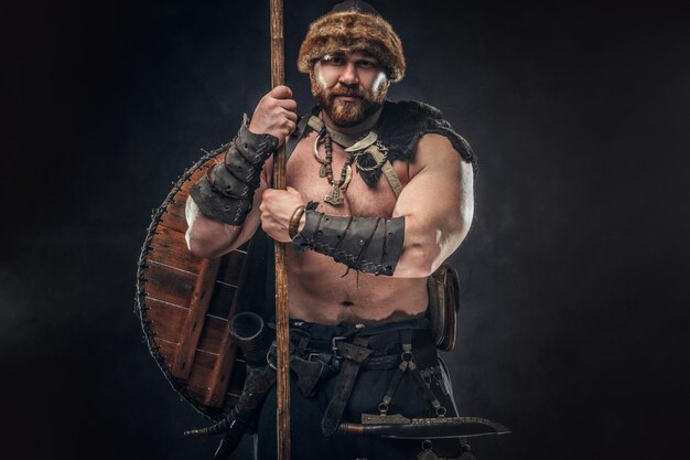 Severe barbarian in warrior clothes, posing on a dark background.