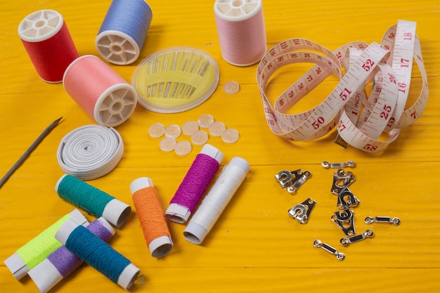 A sewing kit, needle, thread, a needle, placed on a yellow wooden floor.