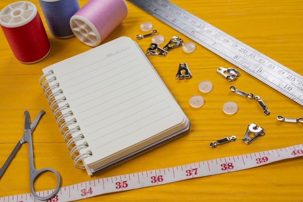 Free photo a sewing kit, needle, thread, a needle, placed on a yellow wooden floor.