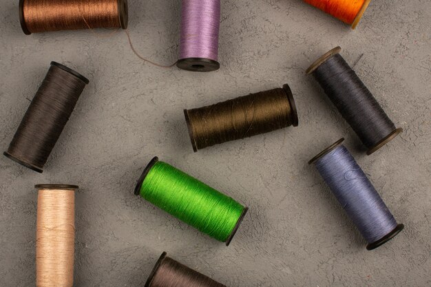 Цветные швейные нитки на сером столе