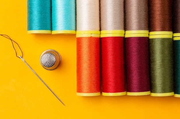 Sewing threads of many colors and a needle thimble placed neatly