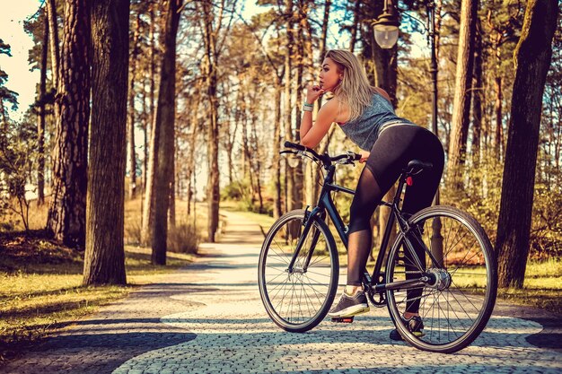 夏の公園で自転車に乗ってセクシーなブロンドの女性