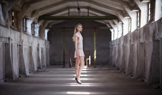 Sexy blond female in cream dress posing in a big hall.