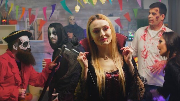 Сексуальная блондинка в костюме чародейки танцует на вечеринке в честь Хэллоуина. Группа людей, празднующих хэллоуин в украшенной комнате.