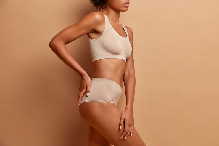 Free Photo sexy body of mixed race woman standing in profile keeps hand on buttocks dressed in underwear has perfect shining skin slim figure
