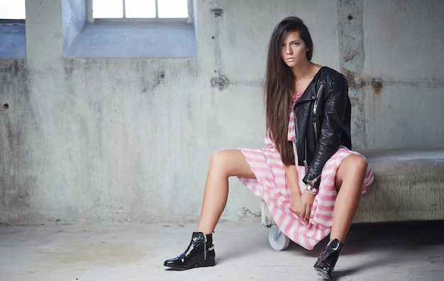 Sexy brunette in pink dress and leather jacket posing on camera.