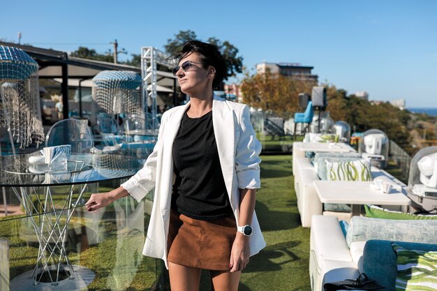 Sexy brunette woman in white jacket, black shirt and leather brown skirt in restaurant.