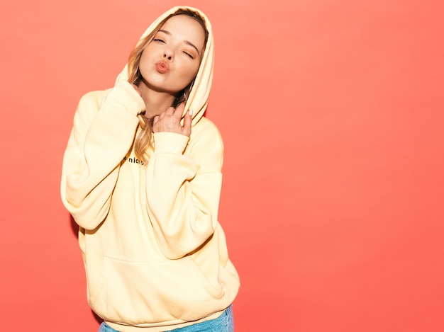 Sexy carefree woman posing near blue wall. Positive model having fun in hood.Makes duck face