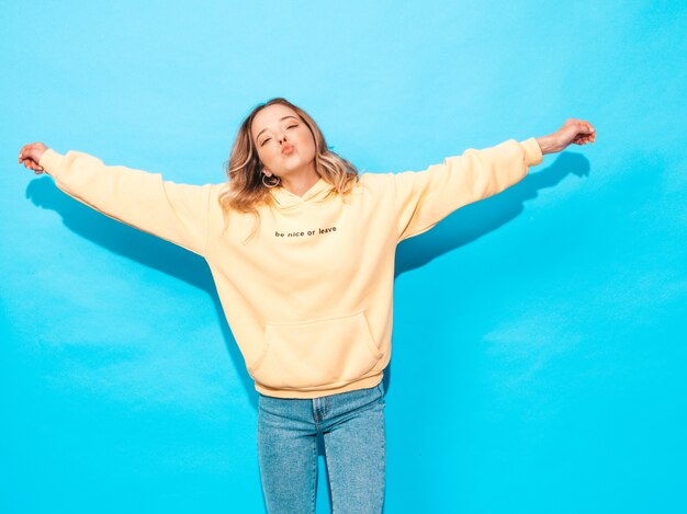 Sexy carefree woman posing near blue wall. Positive model having fun.Raising her hands