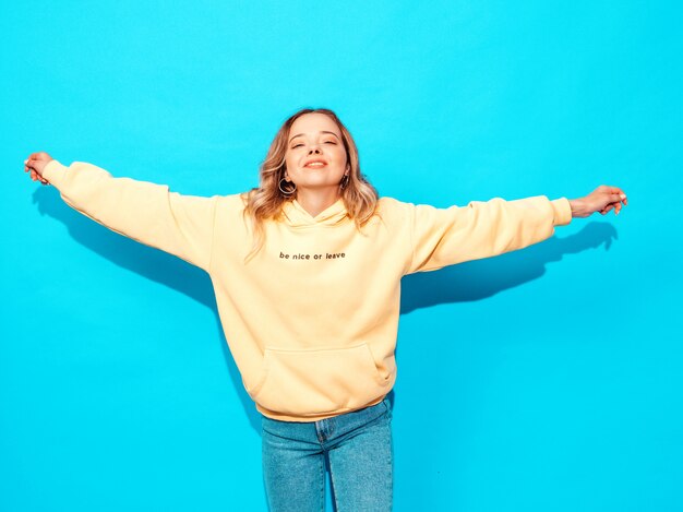 Sexy carefree woman posing near blue wall. Positive model having fun.Raising her hands