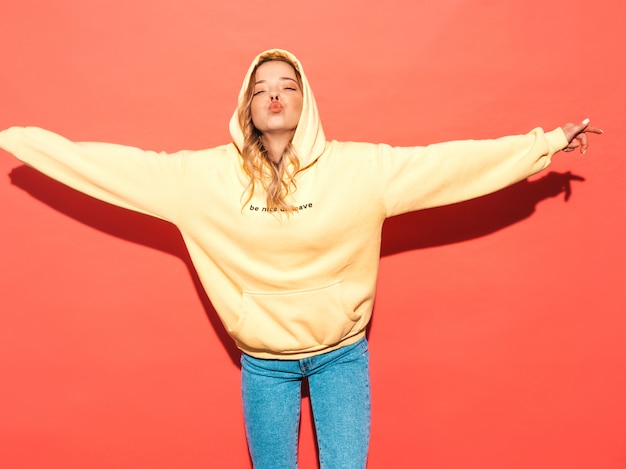 Sexy carefree woman posing near pink wall. Positive model having fun.Raising her hands