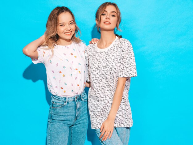 sexy carefree women posing near blue wall. positive models having fun