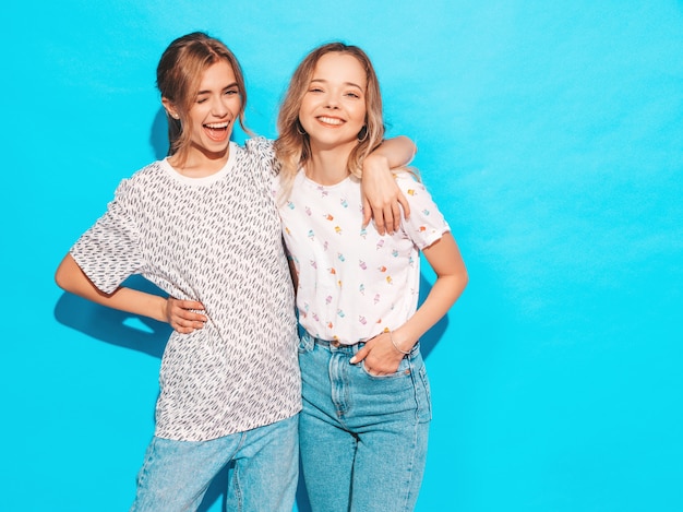 Sexy carefree women posing near blue wall. Positive models having fun