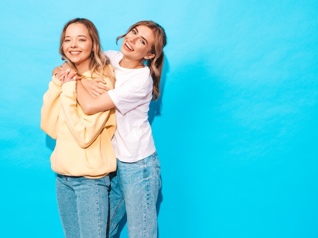 Sexy carefree women posing near blue wall. Positive models having fun