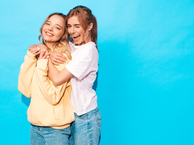 Free photo sexy carefree women posing near blue wall. positive models having fun