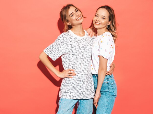 sexy carefree women posing near pink wall. positive models having fun