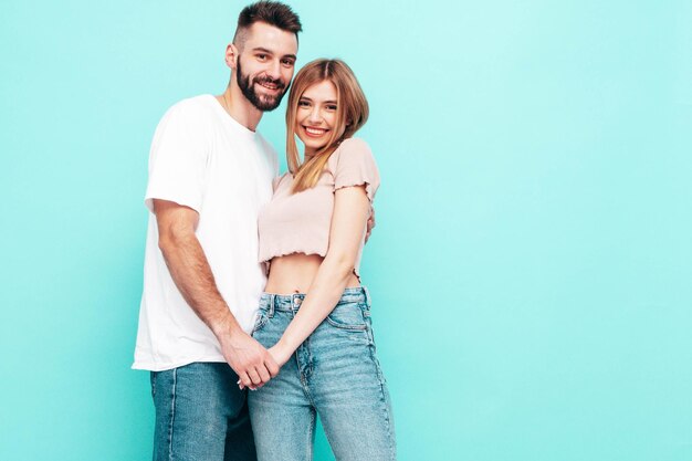 Sexy smiling beautiful woman and her handsome boyfriend Happy cheerful family having tender moments near blue wall in studioPure cheerful models huggingEmbracing each other Cheerful and happy